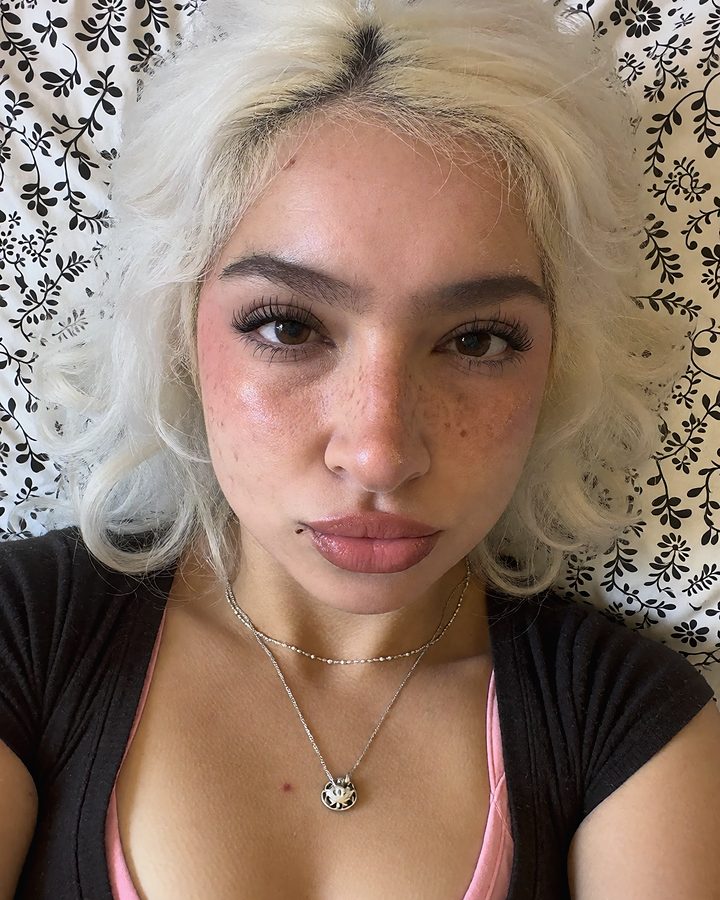 Selfie of a woman with platinum curly hair and freckles.